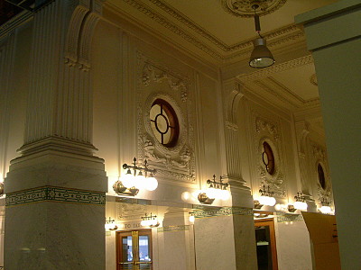 [Ornate round window structures above the hallway which appears to have white marble columns.]